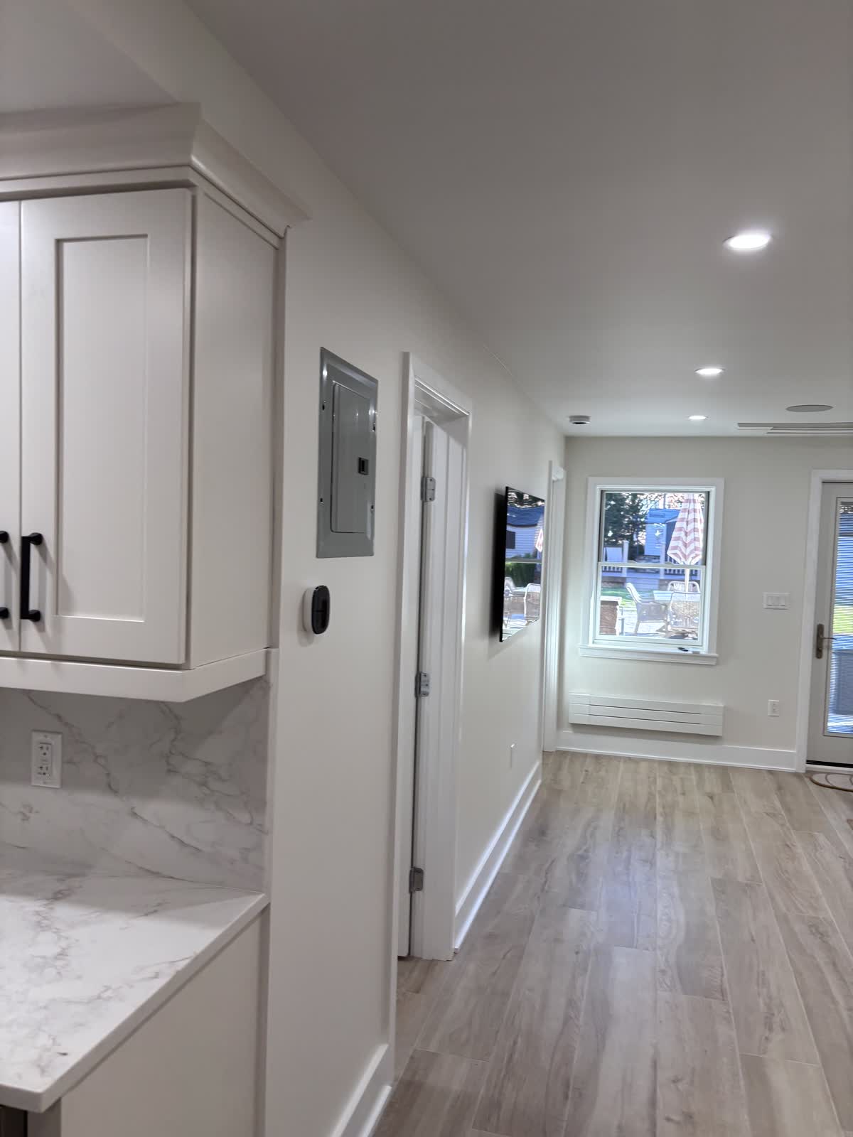 Finished hallway with wood-look floors and recessed lighting leading to a door out to the yard