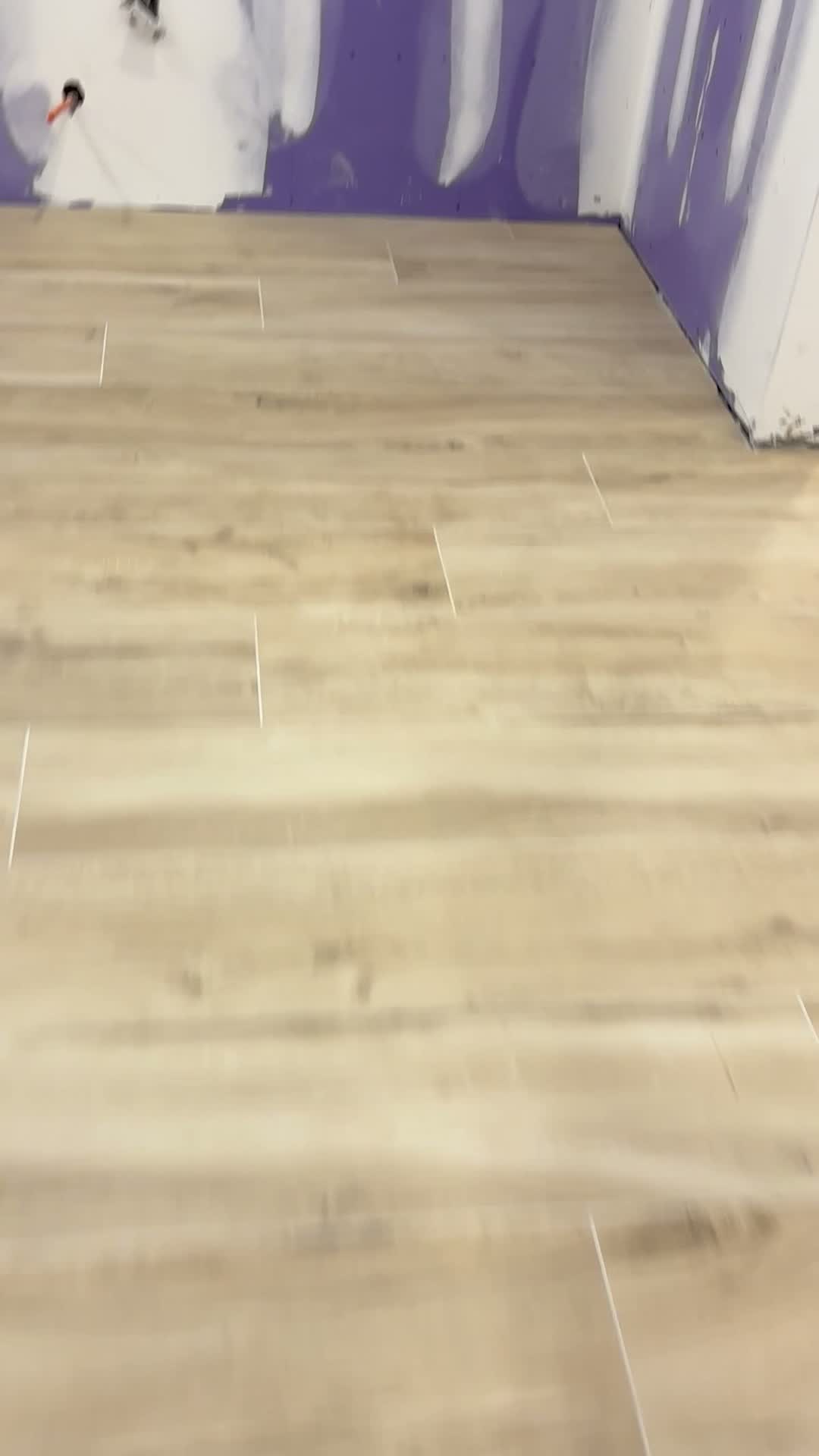 Wood-look plank tile floor installed in a bathroom with taped and spackled walls