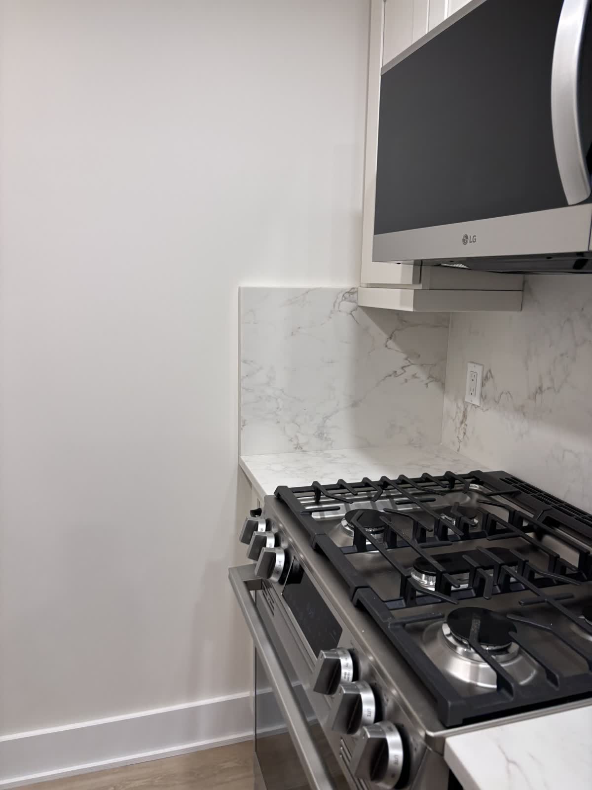 Gas range with a microwave above and a marble-look stone backsplash